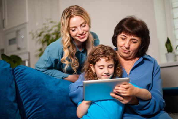 Drei Frauen verschiedener Generationen sitzen vor Tablet und lernen gemeinsam