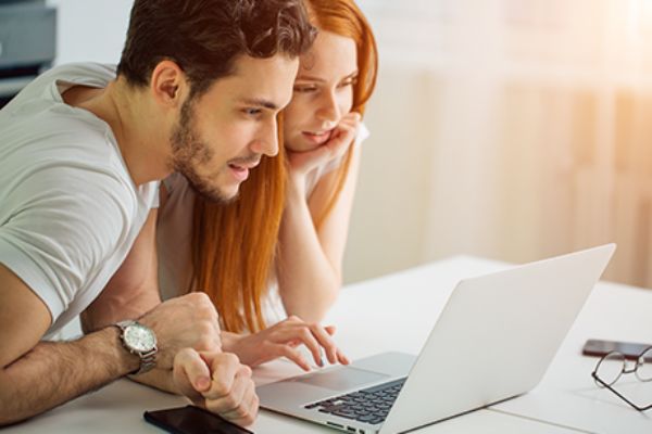 Mann und Frau sitzen vor Laptop