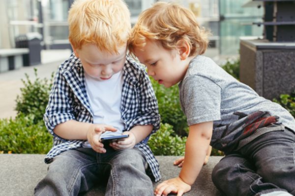 Zwei Kleinkinder spielen mit einem Smartphone