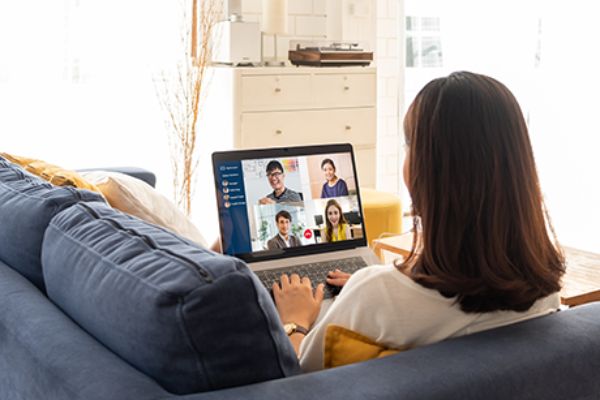 Videokonferenz: eine Frau sitzt auf einem Sofa mit einem Laptop 