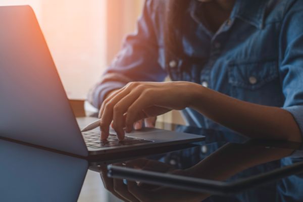 Männlicher Torso sitzt vor offenem Laptop 