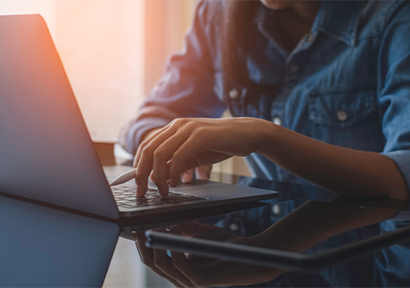 Männlicher Torso sitzt vor offenem Laptop 