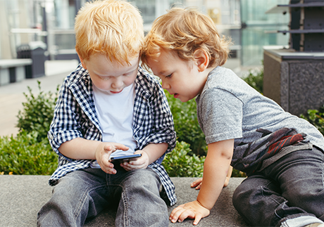 Zwei Kleinkinder spielen mit einem Smartphone