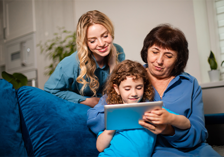 Drei Frauen verschiedener Generationen sitzen vor Tablet und lernen gemeinsam